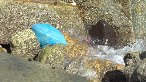 blue plastic bag with food container hit by wave