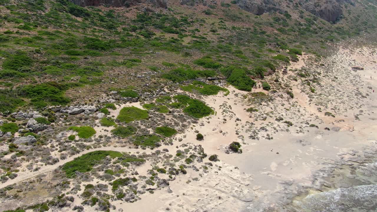 Lagoon shore of Balos Beach with vegetation in Crete Greece where the water meets the land, Aerial approach shot
