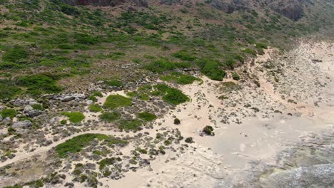 lagoon shore of balos beach with vegetation in crete greece where the water meets the land, aerial approach shot