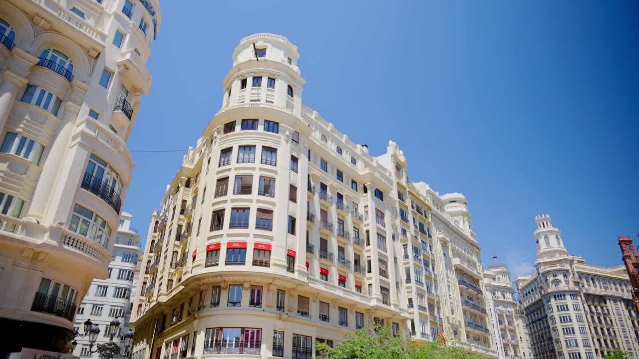 Valencia, Spain - May 29, 2025: Cyclists and pedestrians on a pedestrian boulevard leading toward the landmark towered buildings of Plaza del Ayuntamiento