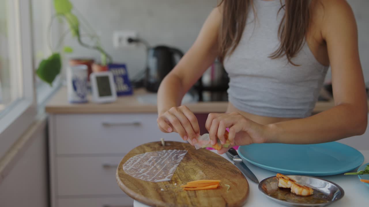 Close-up of a person preparing fresh spring rolls in a kitchen