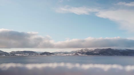 nubes blancas esponjosas sobre el mar en calma y la cordillera en invierno