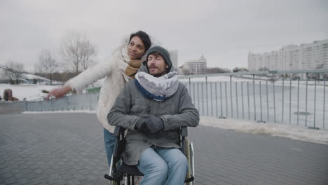 muslim woman and her disable friend looking at something in the sky in city in winter