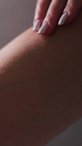 la mujer acaricia la pierna suave en el baño de primer plano. la dama disfruta de la piel suave y hidratada de la pierna sobre un fondo claro. procedimientos de spa para el cuidado del cuerpo y belleza