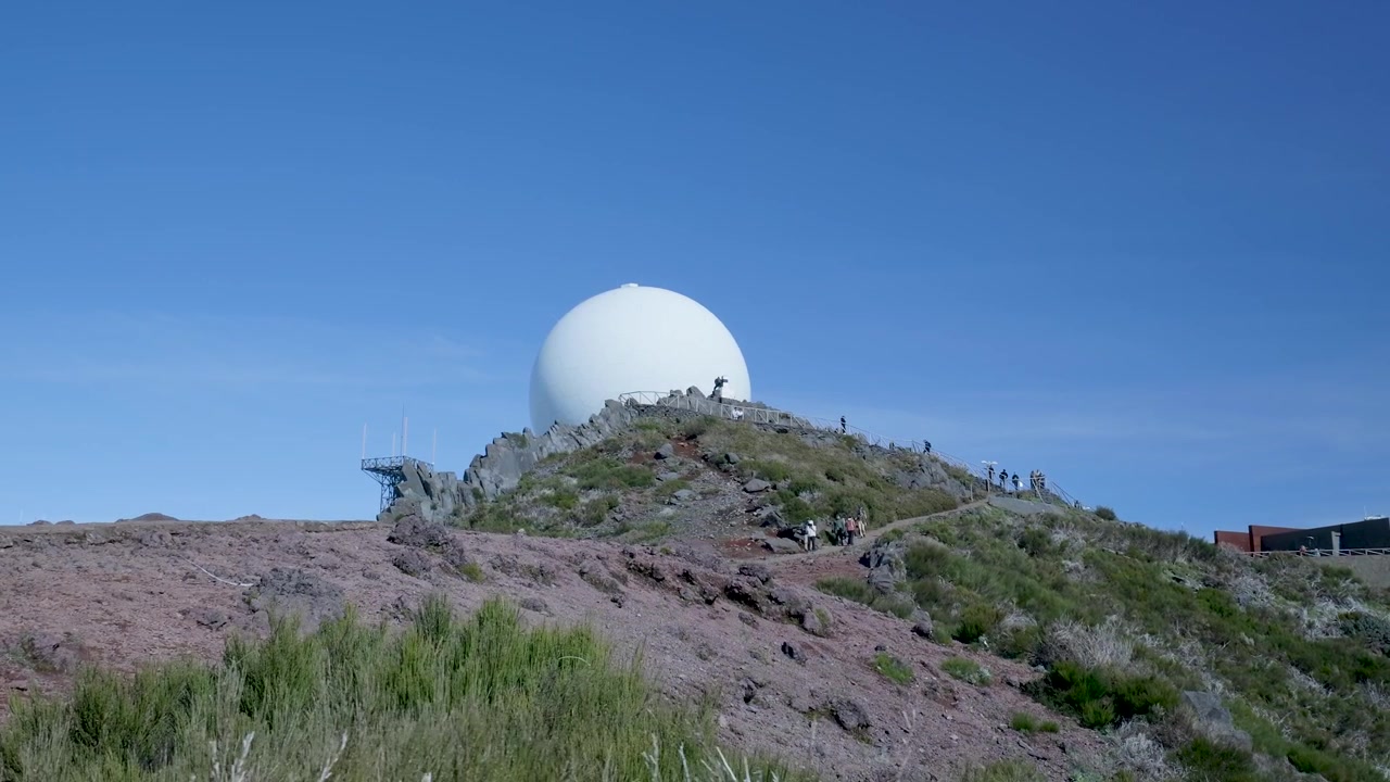 Caminhantes em Trilha Rochosa na Montanha com Grande Cúpula de Radar