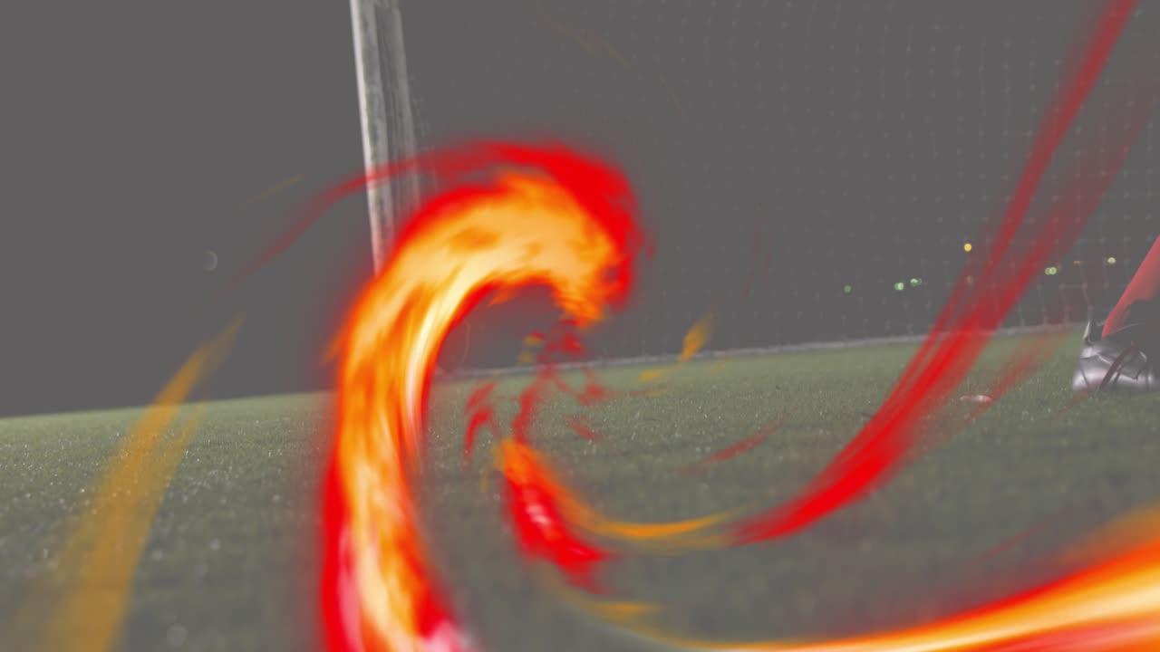 Soccer player shifting weight activating flame swirl around ball launching fiery shot toward goal