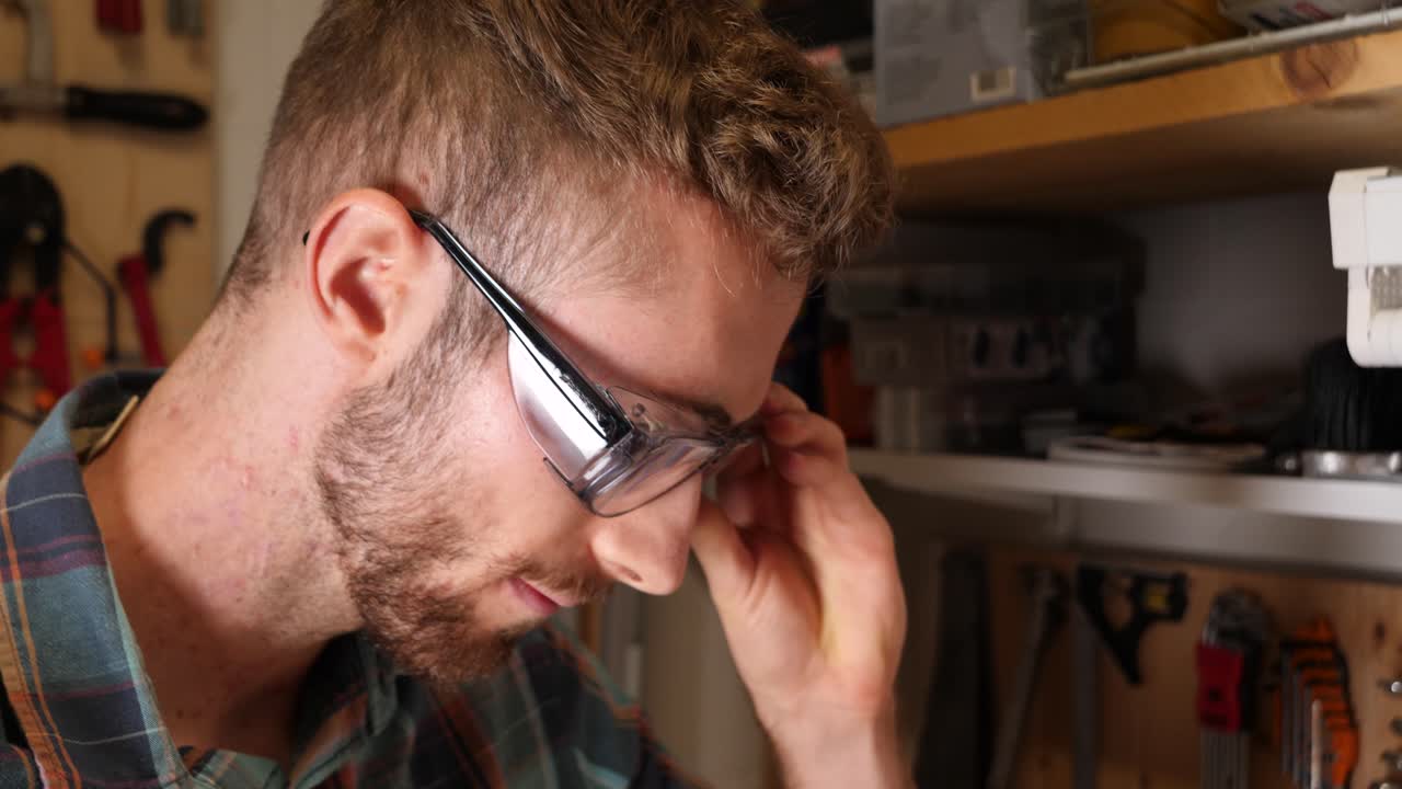 Caucasian man puts on safety glasses to protect his eyes during woodwork