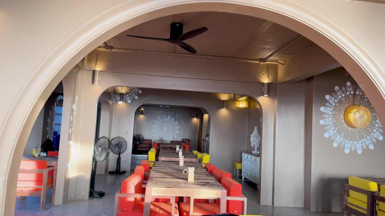 A serene beach club interior with vibrant seating and ambient lighting, captured in Phuket, Thailand. Arched architecture and decorative elements enhance the atmosphere