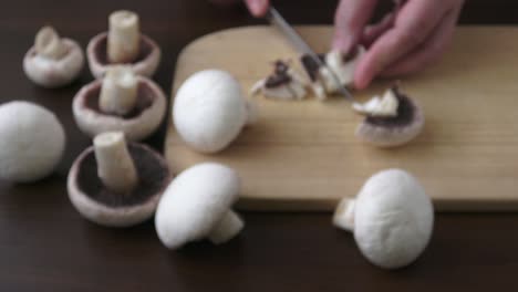 mujer con un cuchillo de cocina, cortando setas descascaradas y blancas