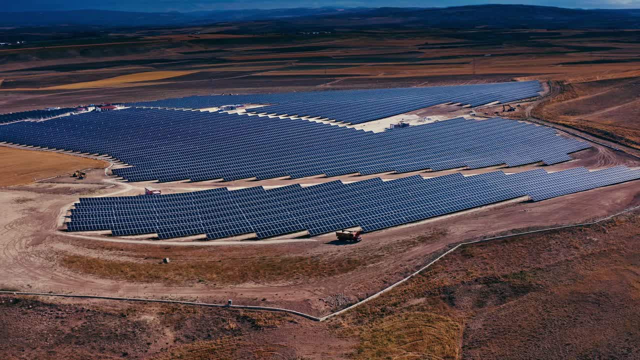 una impresionante vista aérea de una granja solar a gran escala en un paisaje seco, que muestra filas de paneles solares que generan energía limpia y renovable