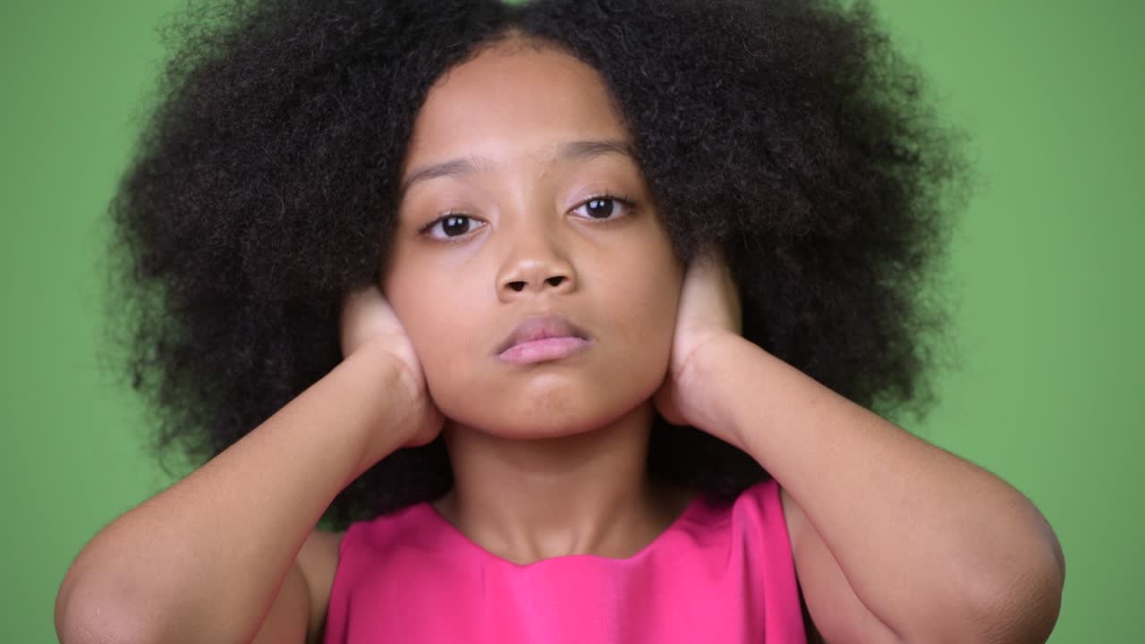 Giovane ragazza africana carina con capelli afro che si copre le orecchie, come nel concetto delle tre scimmie sagge