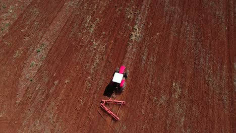 Drone-Aéreo-Siguiendo-Desde-Arriba-Un-Tractor-Preparando-El-Suelo-Para-La-Siembra-De-Semillas-Haciendo-Curvas