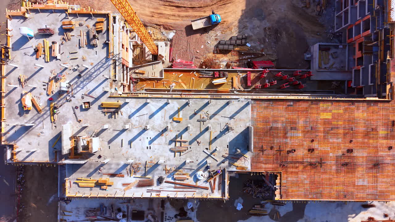 Building floor with rebar reinforcement, crane and a blue truck nearby. Aerial top down view of building construction site