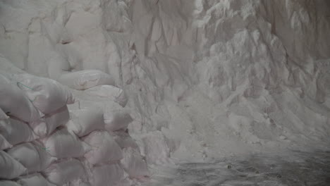bolsas apiladas de sal marina en un almacén cerca de un montón de sal