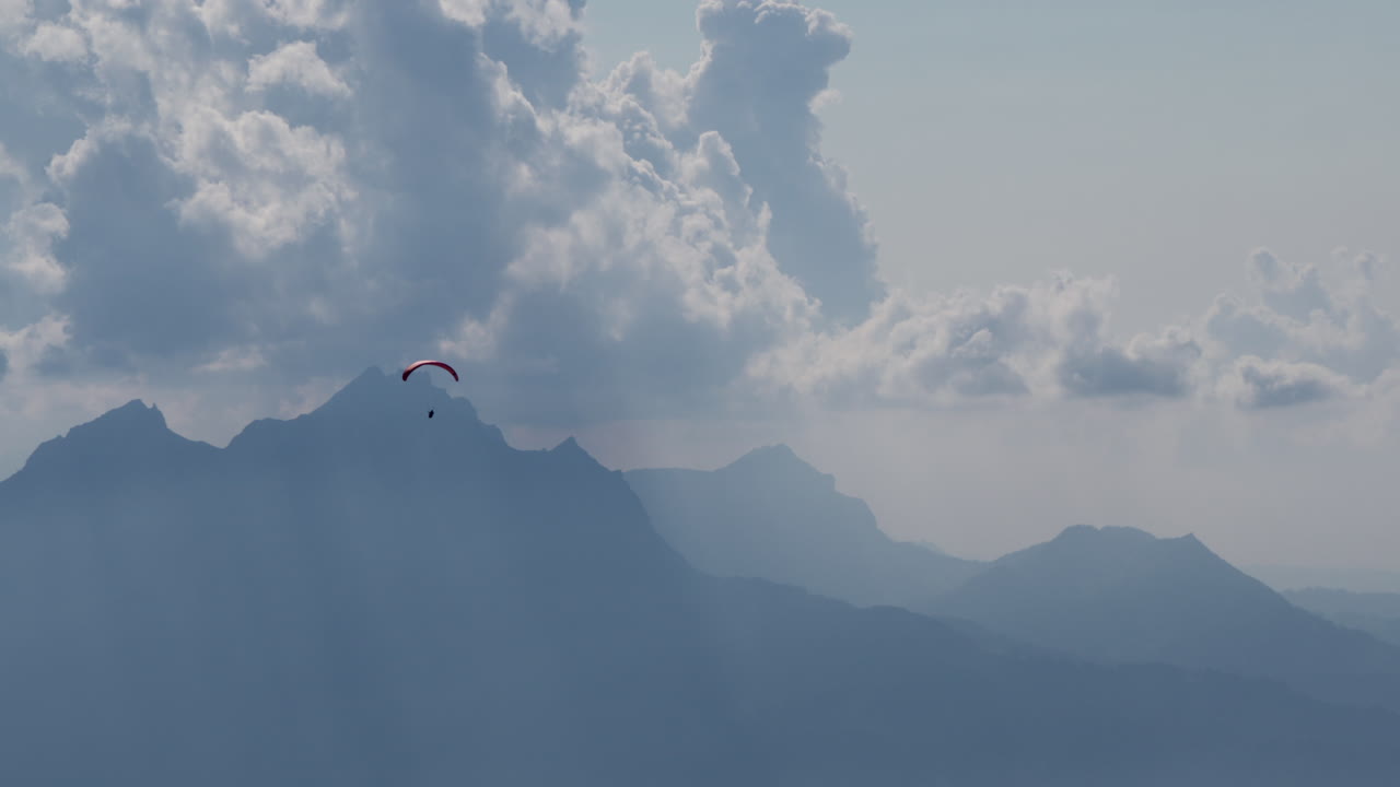 패러글라이더가 산과 구름 위를 날고 있다
