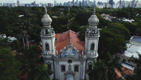 Aerial-view-in-front-of-the-Igreja-Nossa-Senhora-do-Brasil,-with-Sao-Paulo-cityscape-background---tilt,-drone-shot