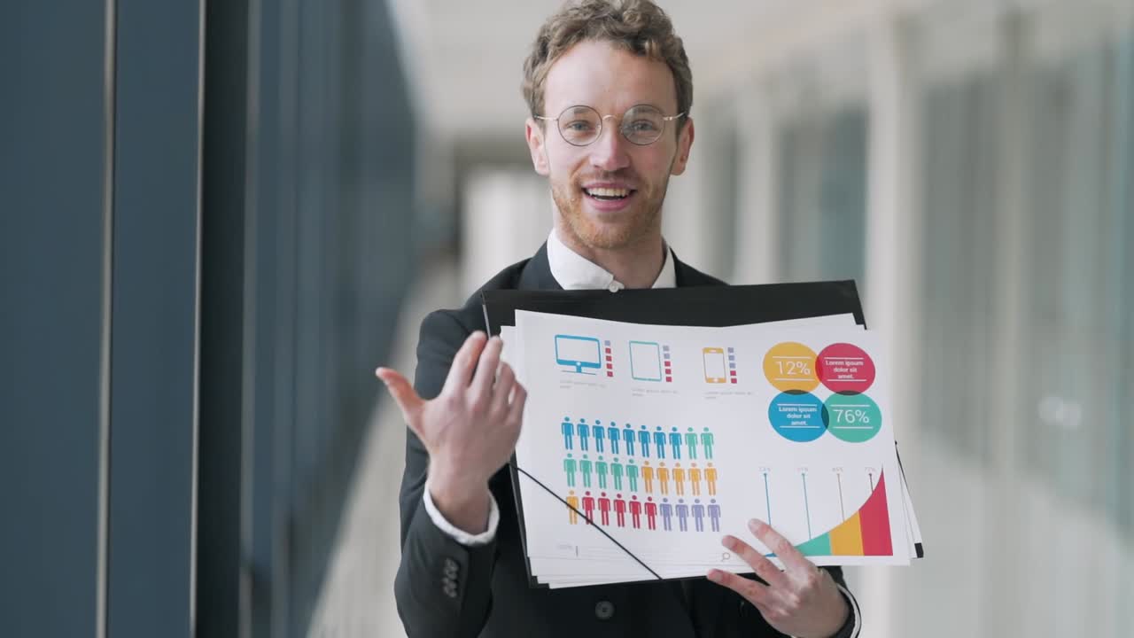 buen joven sosteniendo diapositivas con infografías dando una presentación mirando a la cámara