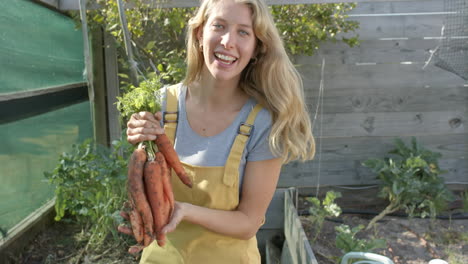 portrait of happy caucasian woman working in garden and picking carrots, slow motion