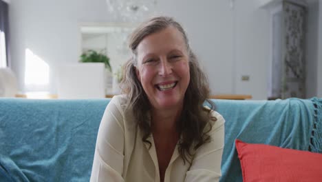 Portrait-of-happy-senior-caucasian-woman-sitting-in-living-room-smiling