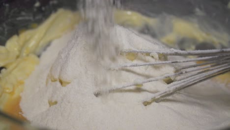 slow motion, home baker pouring flour in a bowl with ingredients