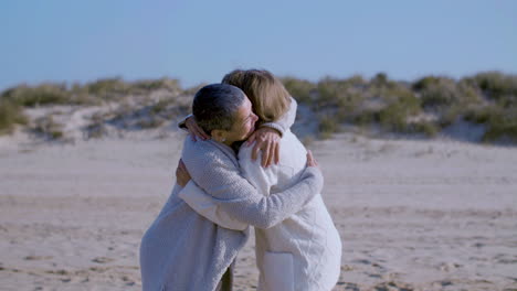 happy senior women hugging on sandy beach