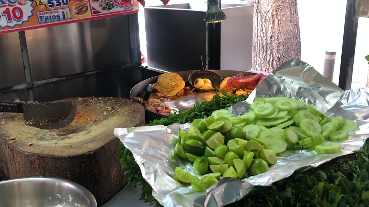 puesto de comida callejera mexicana con carne a la parrilla, tabla de cortar, limas y verduras para preparar deliciosos tacos