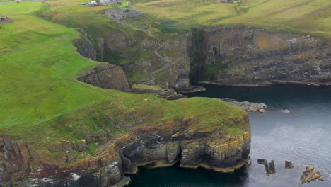 revealing drone shot of whaligoe haven and the rocky 250ft cliffs overlooking the north sea in scotland