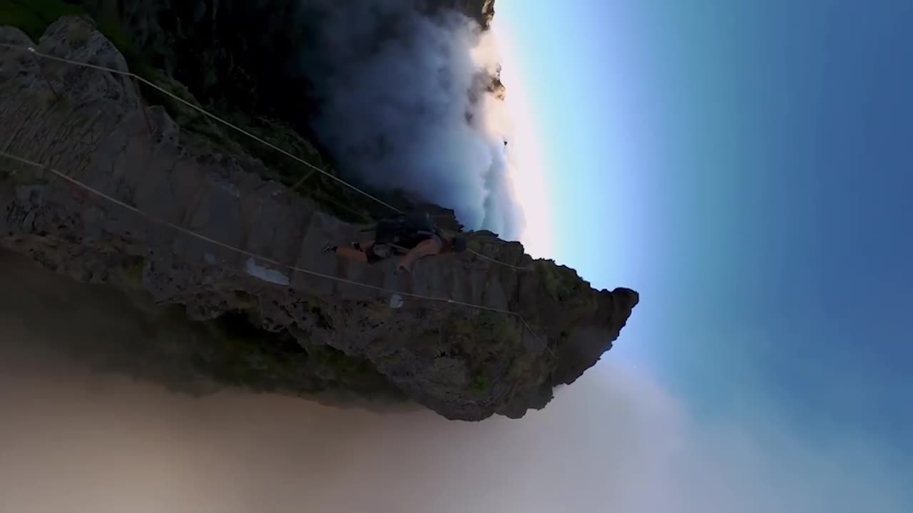 Vertical 360 footage of a man hiking up the steps from Pico do Arieiro to Pico Ruivo during sunrise with fog, smoke, mist and clouds around him.