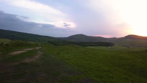 Vista-Aérea-De-Un-Amplio-Valle-Mientras-El-Sol-Se-Pone-Detrás-De-Las-Montañas-En-El-Fondo,-Transilvania,-Rumania---Pan