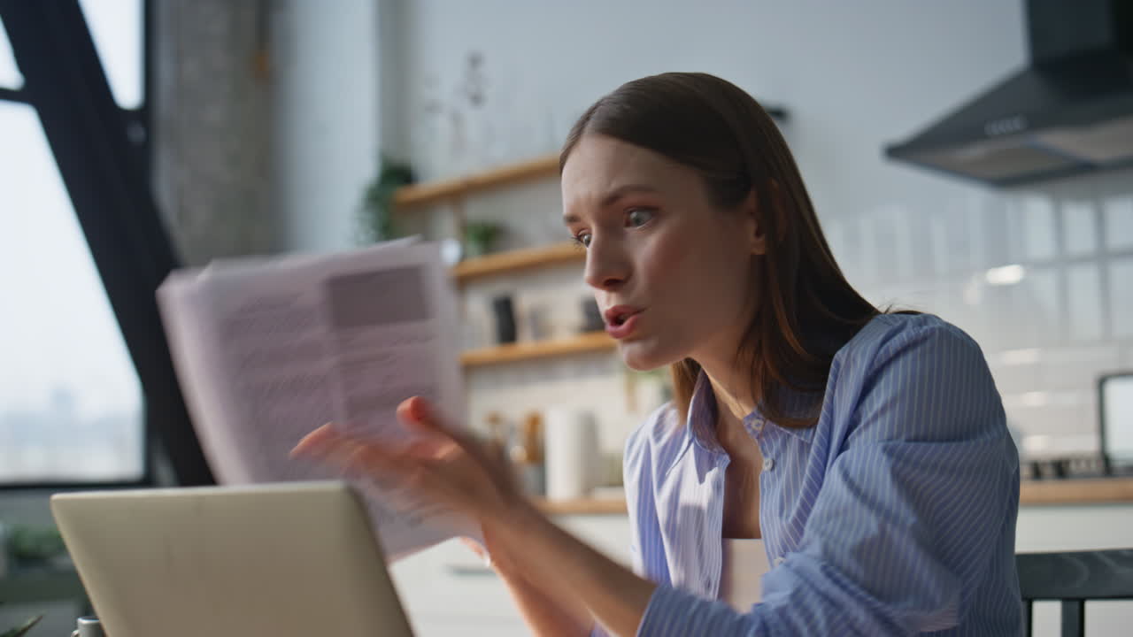 Nervous lady ceo videocalling by laptop dissatisfied documents at home closeup