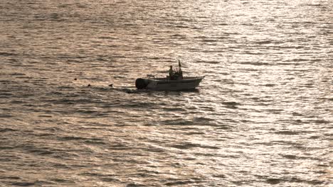 small boat in the ocean backlit at sunrise with small waves