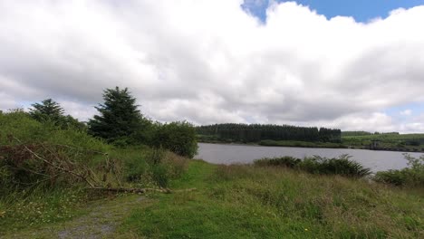 Sunny-Alwen-Embalse-Timelapse-Nubes-Rápidas-Que-Pasan-Sobre-El-Vasto-Agua-Del-Lago-Azul-Del-Bosque-Hacia-La-Cámara