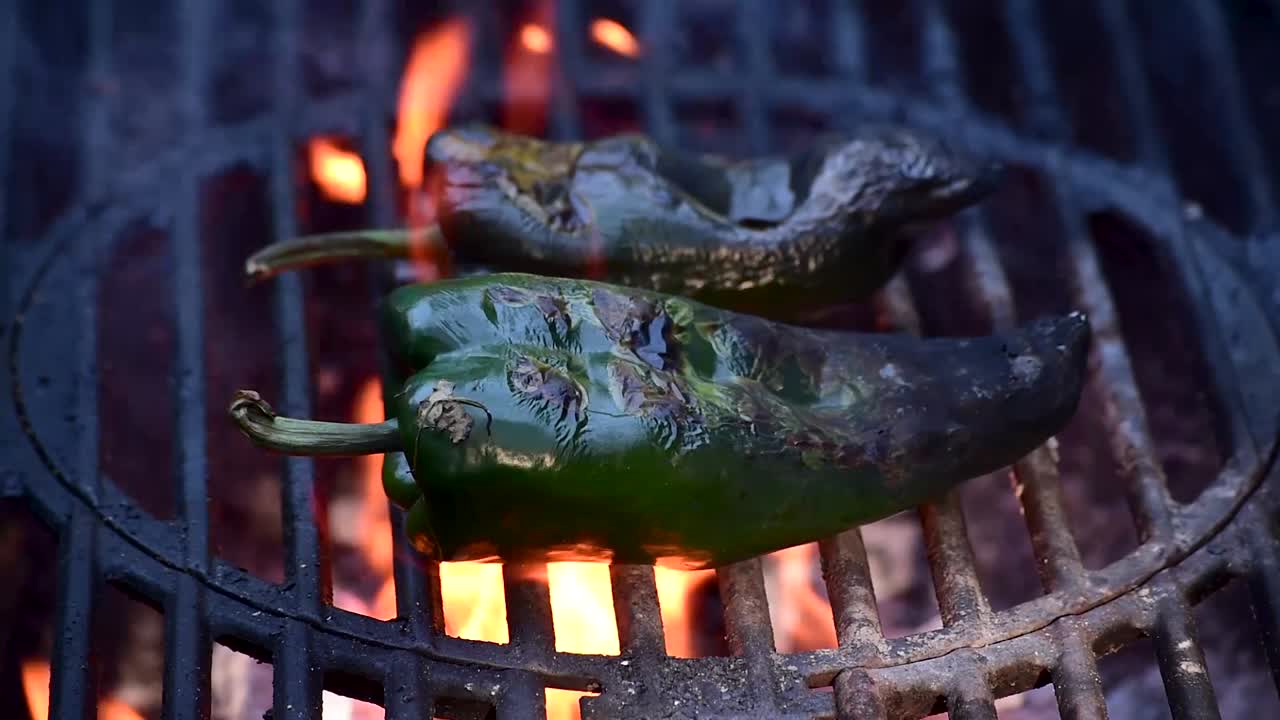 chiles poblanos con marcas de parrilla en el primer plano de la parrilla al aire libre que muestra llamas y humo con espacio para copiar