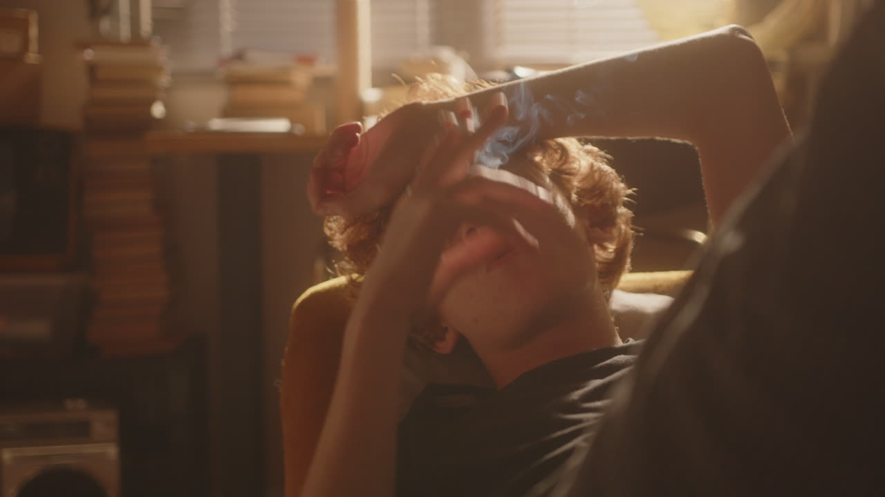 Young Sad Man in Depression Resting on Couch and Smoking Cigarette