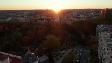 Backwards-reveal-of-apartment-buildings-near-park.-Elevated-view-of-city-against-setting-sun.