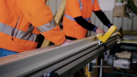 two man placing a wooden rod on a machine