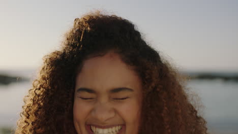 retrato de una mujer joven de raza mixta riendo emocionada disfrutando de un día soleado en la playa