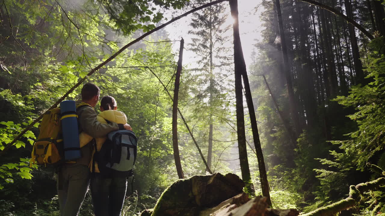 한 젊은 부부가 숲 속의 경치 좋은 길을 걷고 있다