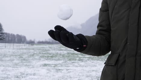 Toma-En-Cámara-Lenta-De-Una-Persona-Con-Guantes-De-Invierno-Lanzando-Bolas-De-Nieve,-Lista-Para-Lanzar