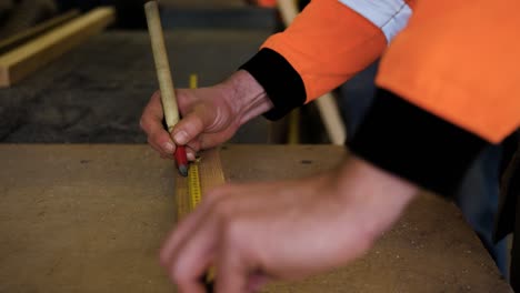 man is measuring a wooden stick