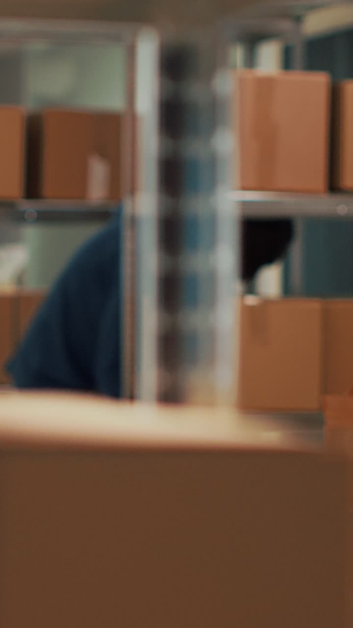 Vertical video: Male owner putting goods in cardboard boxes from shelves