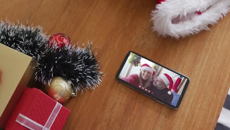 Lächelnder-Kaukasischer-Vater-Mit-Tochter,-Die-Weihnachtsmützen-Trägt,-Bei-Einem-Weihnachtsvideoanruf-Auf-Dem-Smartphone
