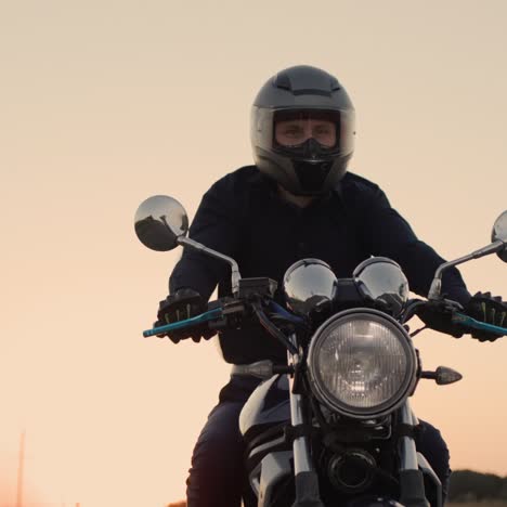 motociclista em uma jaqueta preta cavalga ao pôr do sol 1