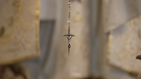 close-up of a crucifix pendant hanging, symbolizing christian faith, with a blurred background