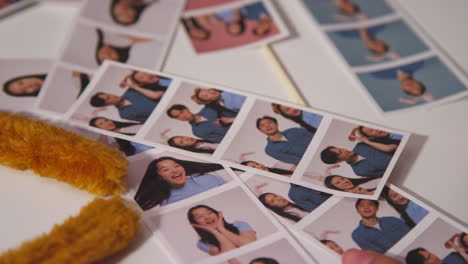 close up of a group of friends having fun looking at prints from photo booth with props 4