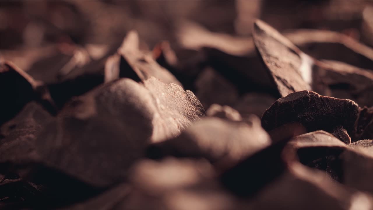 Chunks of sweet dark chocolate sliding backdrop, close-up. Gourmet dessert ingredient.