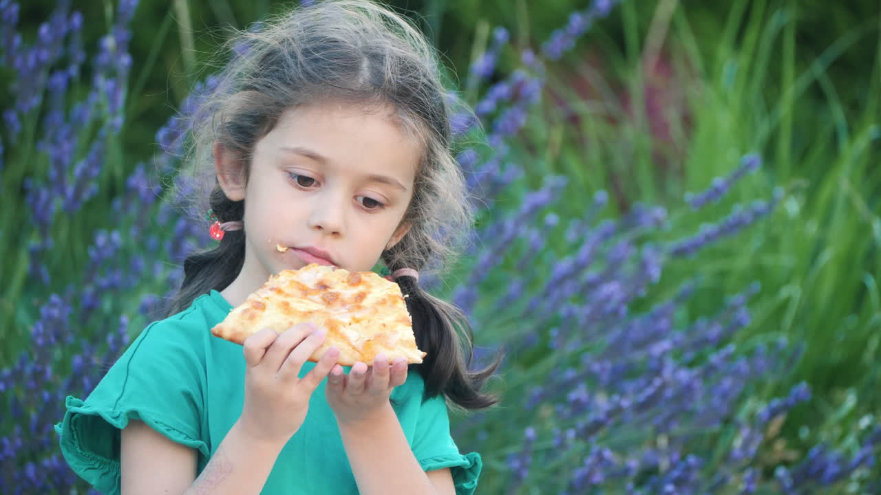 niña comiendo pizza en un pequeño jardín