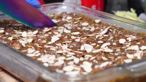 slicing freshly baked caramel banana cake with almond nut toppings