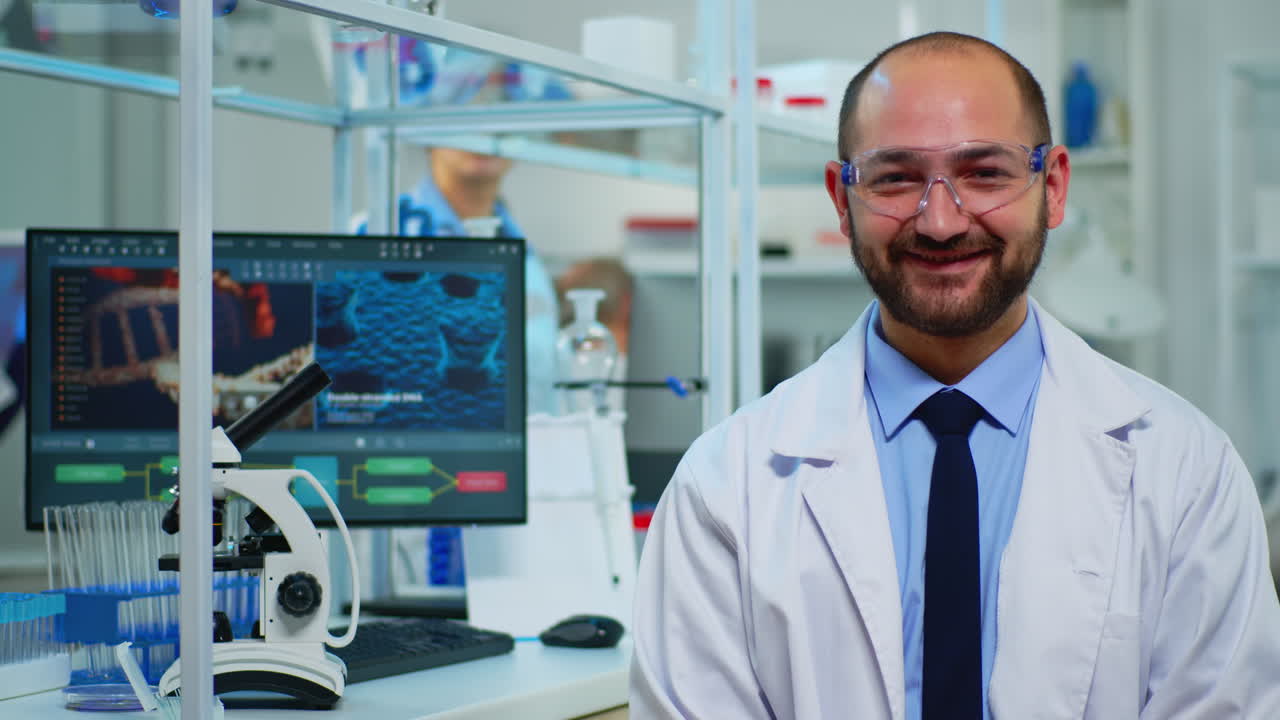 Portrait of scientist man smiling at camera sitting in modern laboratory