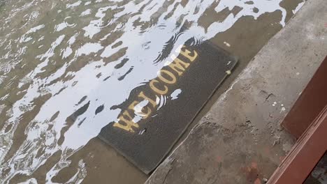 A-welcome-doormat-sign-underwater-after-heavy-rain-storm,-flash-flooding-and-tropical-cyclone-on-remote-tropical-Timor-Leste,-South-East-Asia